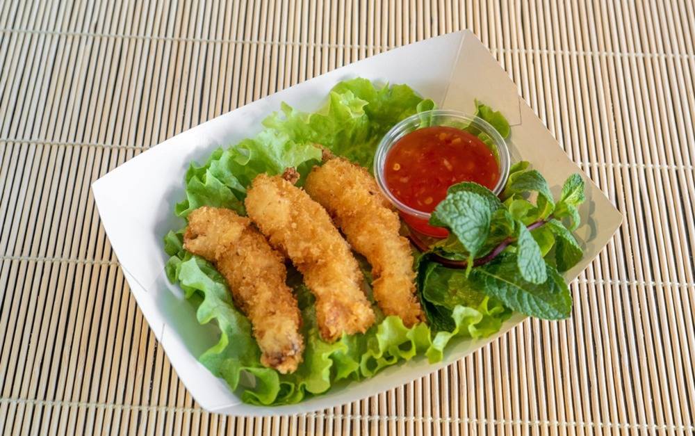 Beignets croustillants servis sur lit de salade avec sauce sweet chili