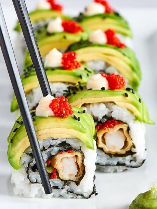 Sushi rolls à l'avocat et tobiko, servis avec des baguettes chez OISHI SUSHI