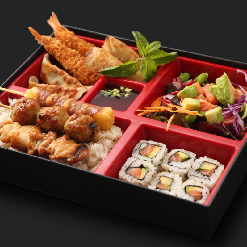 Bento japonais garni de sushi rolls, tempura, brochettes yakitori et salade colorée