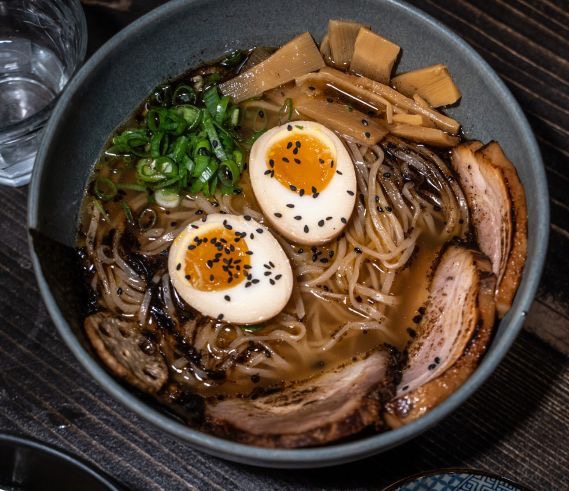 Bol de ramen avec œufs mollets, porc tranché, pousses de bambou et oignons verts