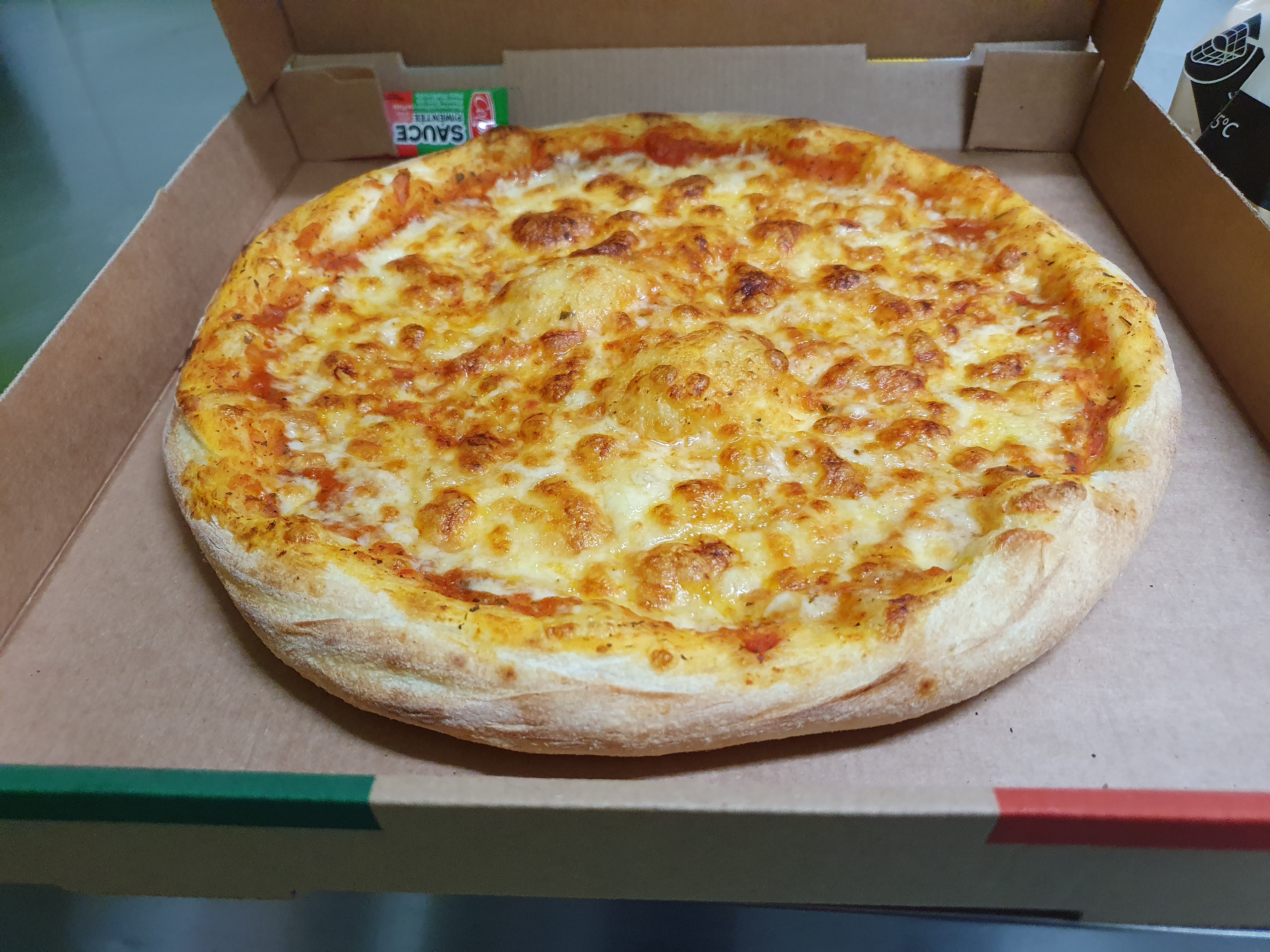 Pizza au fromage fondant dorée au four dans son carton