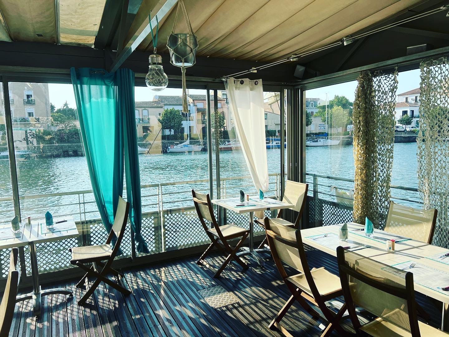 Salle de restaurant La Marina avec vue panoramique sur l'Hérault à travers les baies vitrées