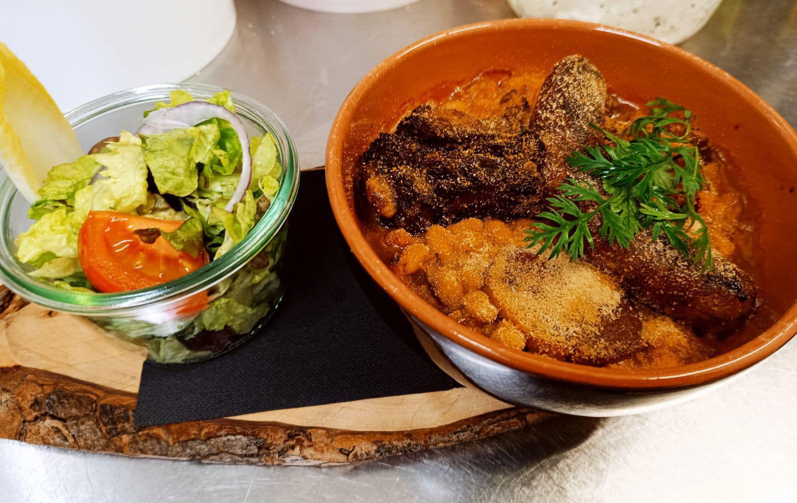 Cassoulet maison servi en cocotte en terre cuite avec salade fraîche sur planche en bois