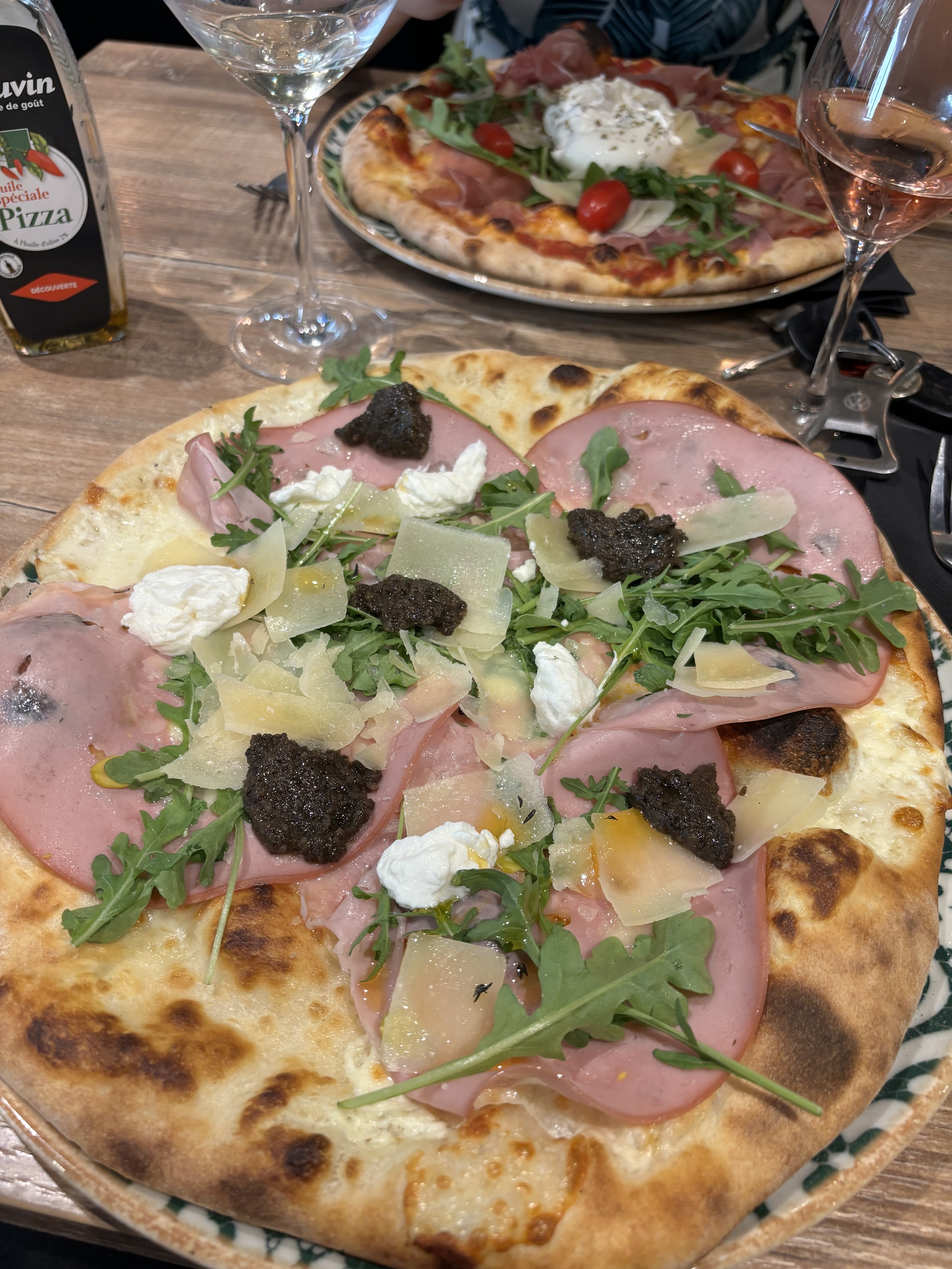 Deux pizzas garnies de mortadelle, roquette, burrata et parmesan sur une table en bois