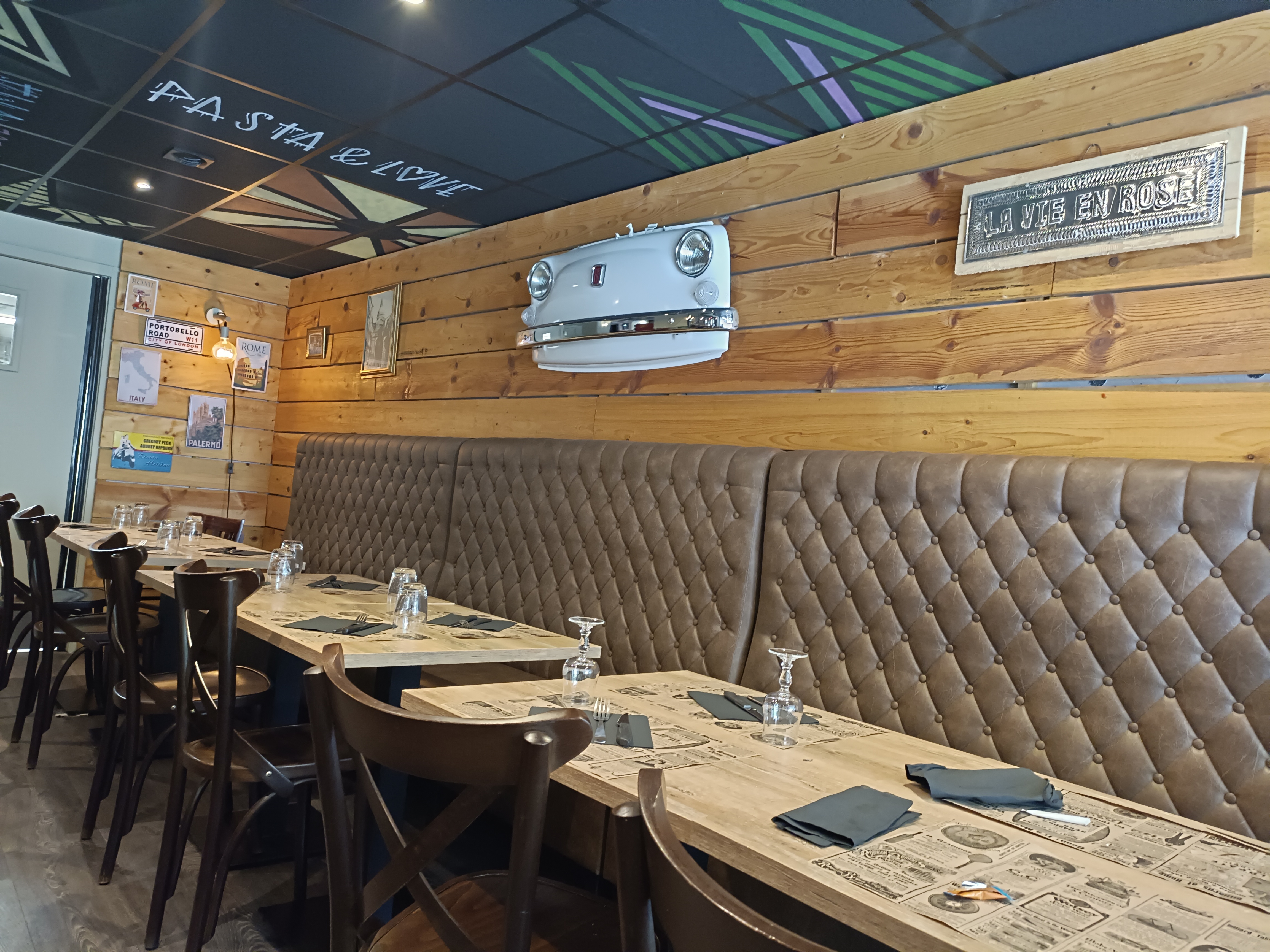Intérieur du restaurant avec banquettes en cuir, murs en bois et décoration vintage italienne