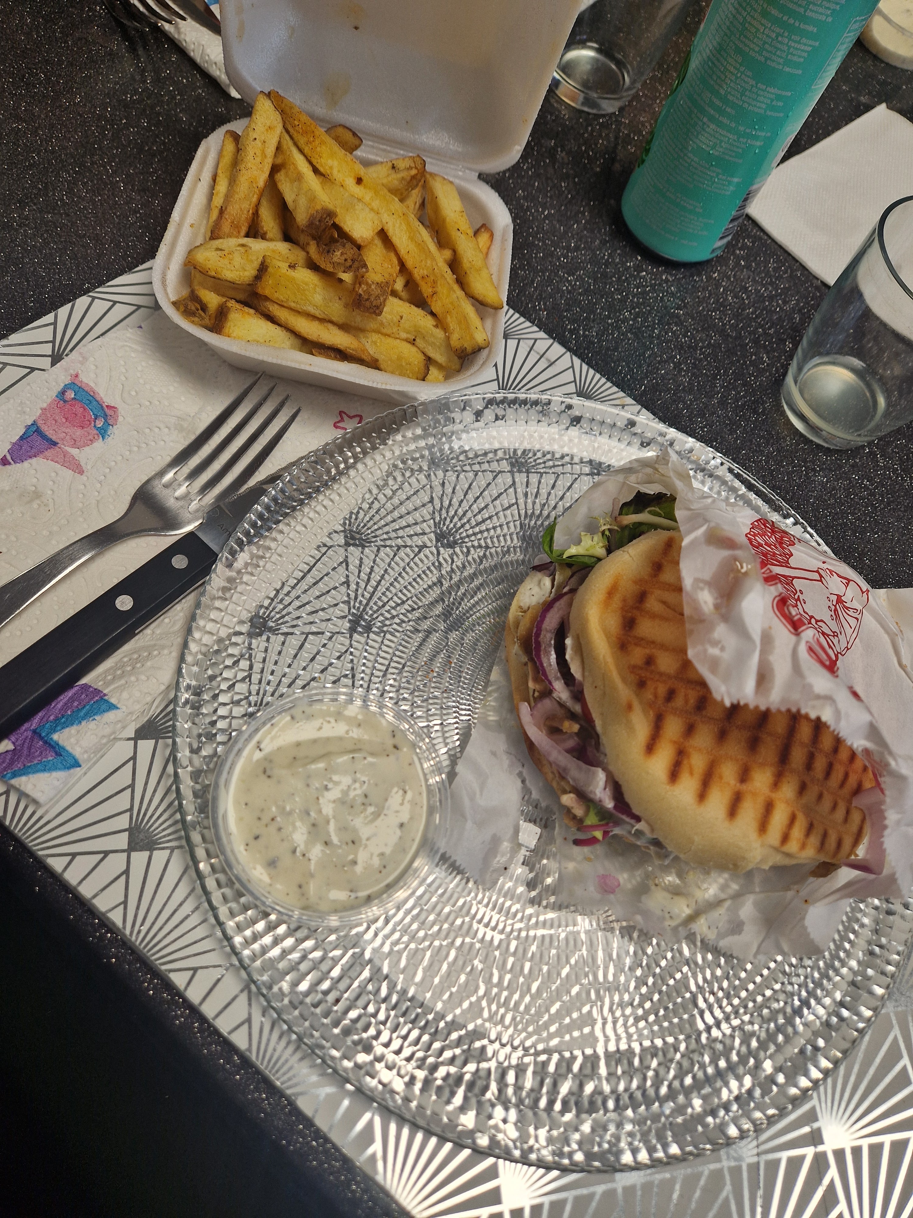 Sandwich pita grillé avec viande et oignons rouges accompagné de frites maison